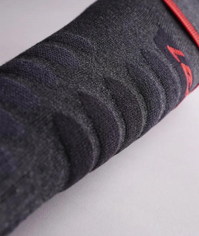 Détail d'une chaussette gris foncé avec un motif à côtes et une touche de rouge.