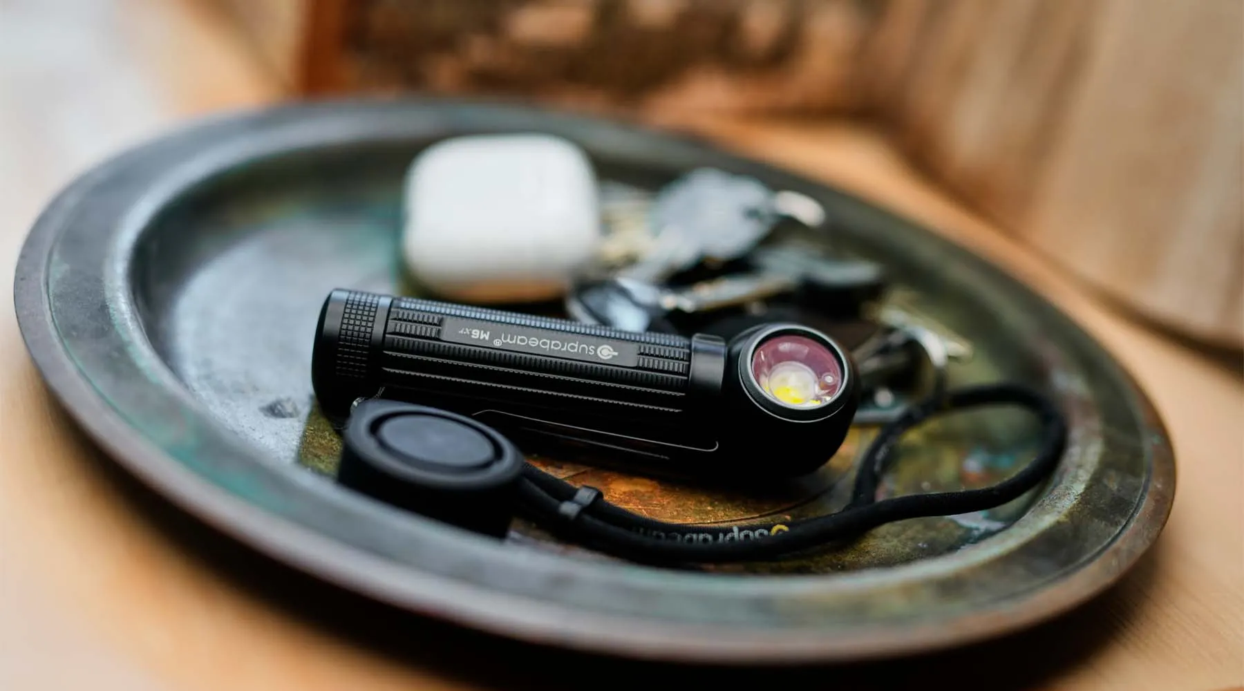Eine Suprabeam M6xr BodyGuard Lampe liegt auf einer kleinen Metallablage.
