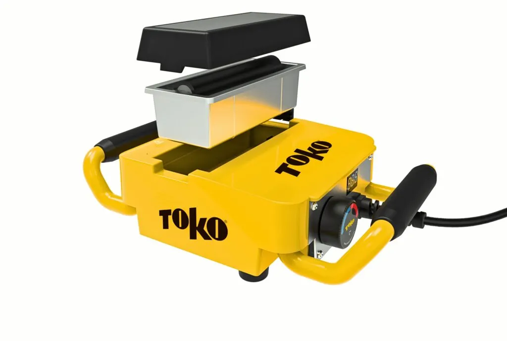 Yellow waxing machine with black lettering and two black handles. Wax roller and lid hover above.
