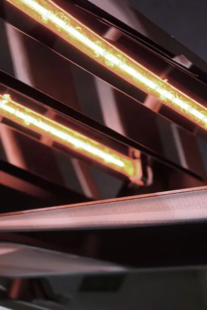 Close-up: Parallel fluorescent tubes in copper holders. Soft, warm light.