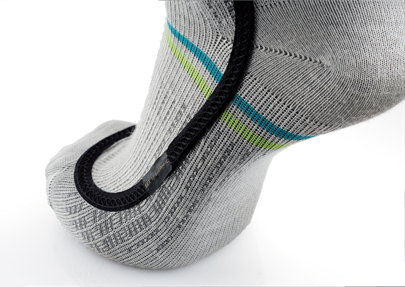 Detailaufnahme einer grauen Ski Heat Race S.E.T Socke mit blauen und grünen Streifen und schwarzem Heizelement.