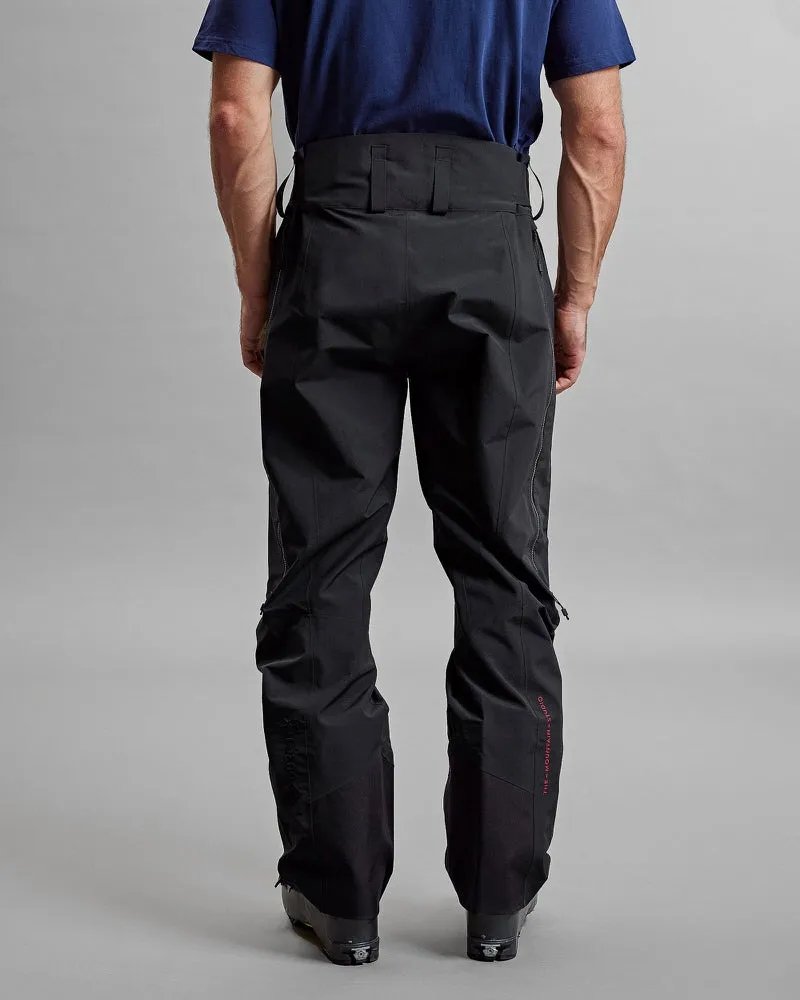 Vue arrière : personne portant le pantalon noir Y-1 HD GORE-TEX Pro 3L Shell, pantalon avec fermetures éclair et logo de marque discret.