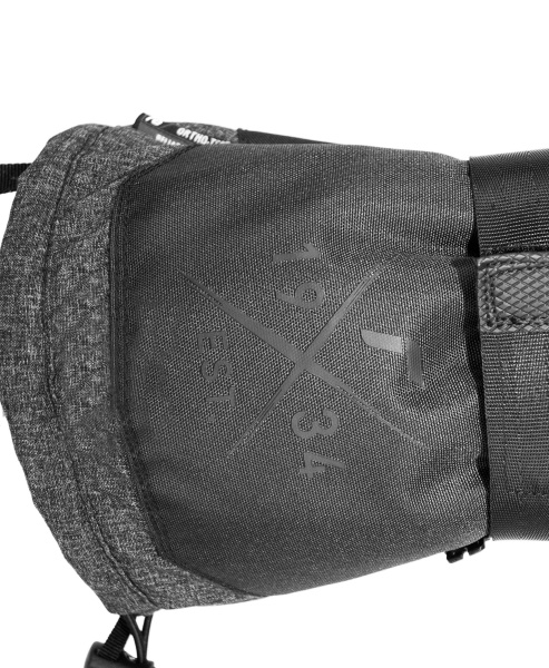 Detailaufnahme einer grauen Tasche mit dem Aufdruck "EST. 1984" in gekreuzten Linien.