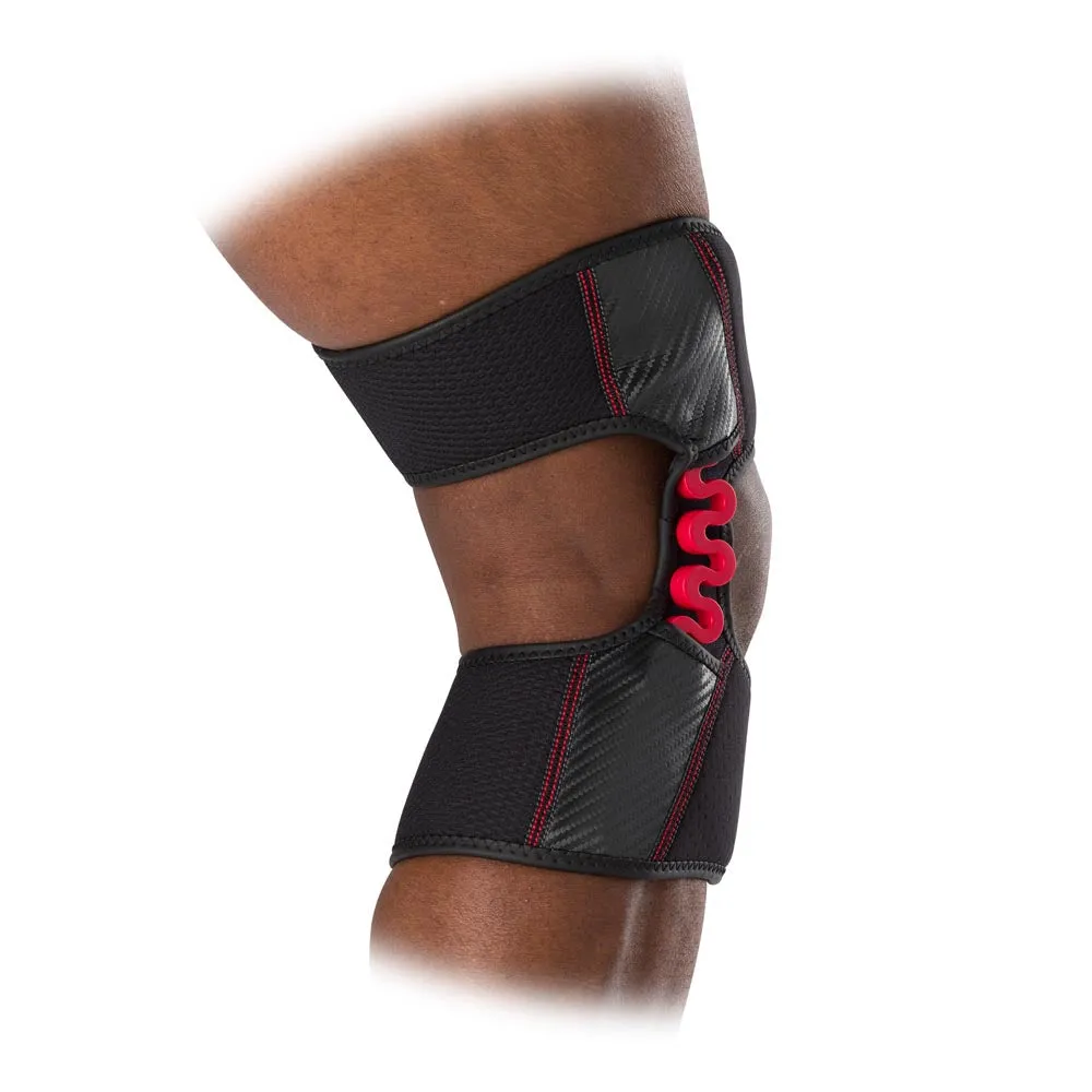 Close-up of a knee with black MCDavid NRG Knee Over Wrap Bandage and red spring hinge.
