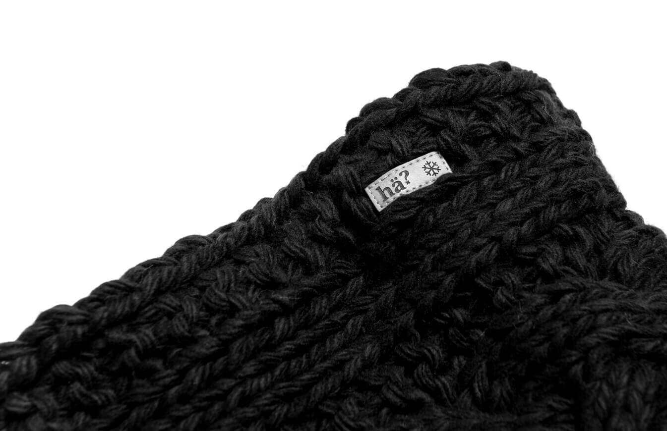 Close-up of the black stroller neckwarmer with label and chunky knit pattern.