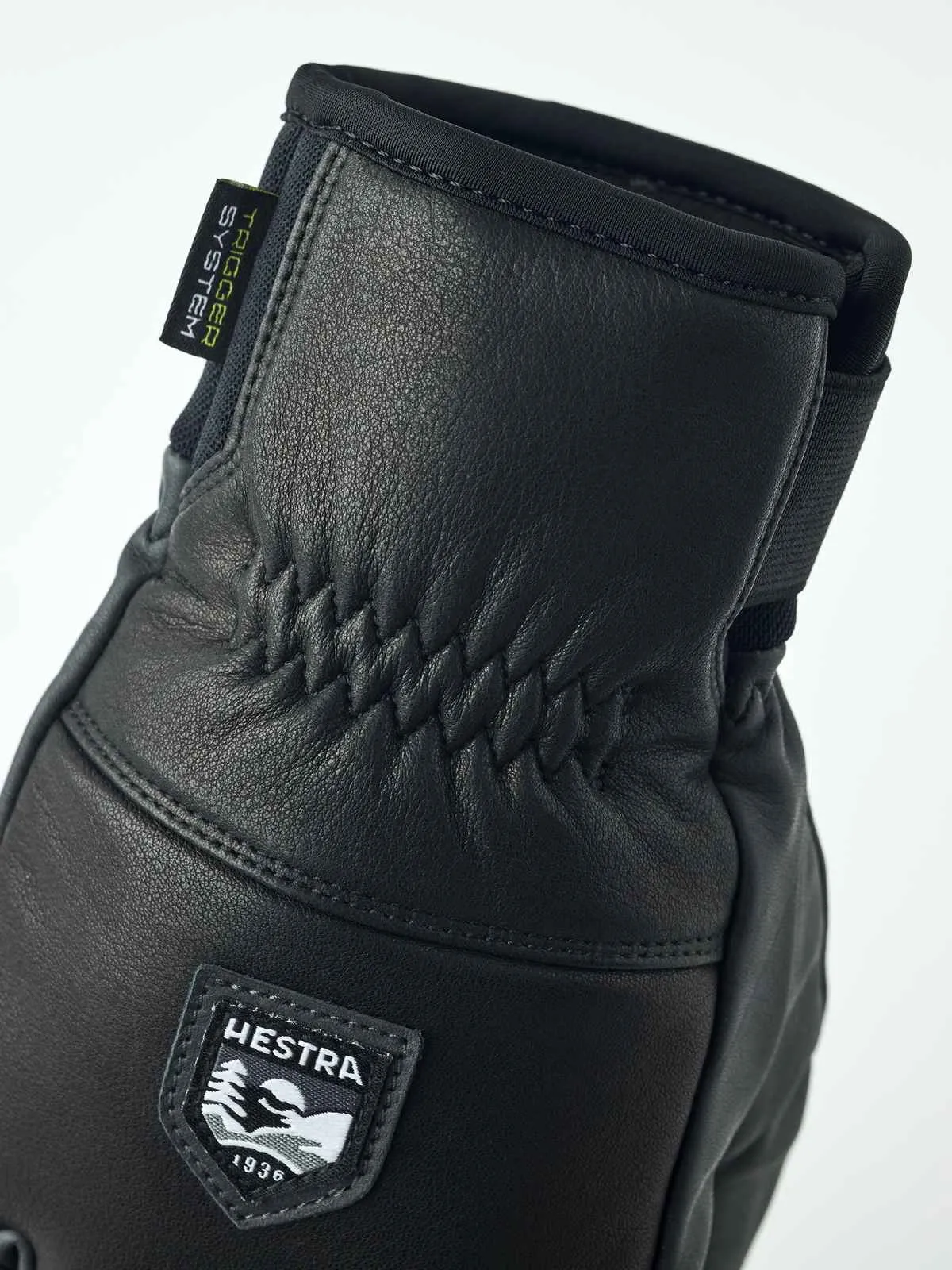 Primo piano di un guanto Hestra Omni Trigger in pelle nera con logo del marchio.