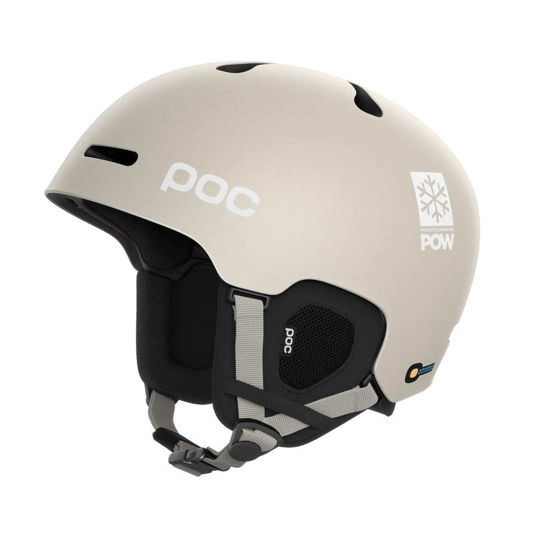 Ein matter, hellgrauer POC Fornix Mips Skihelm. Das POC Logo und ein "Protect Our Winters" Schneeflocken-Logo sind aufgedruckt.