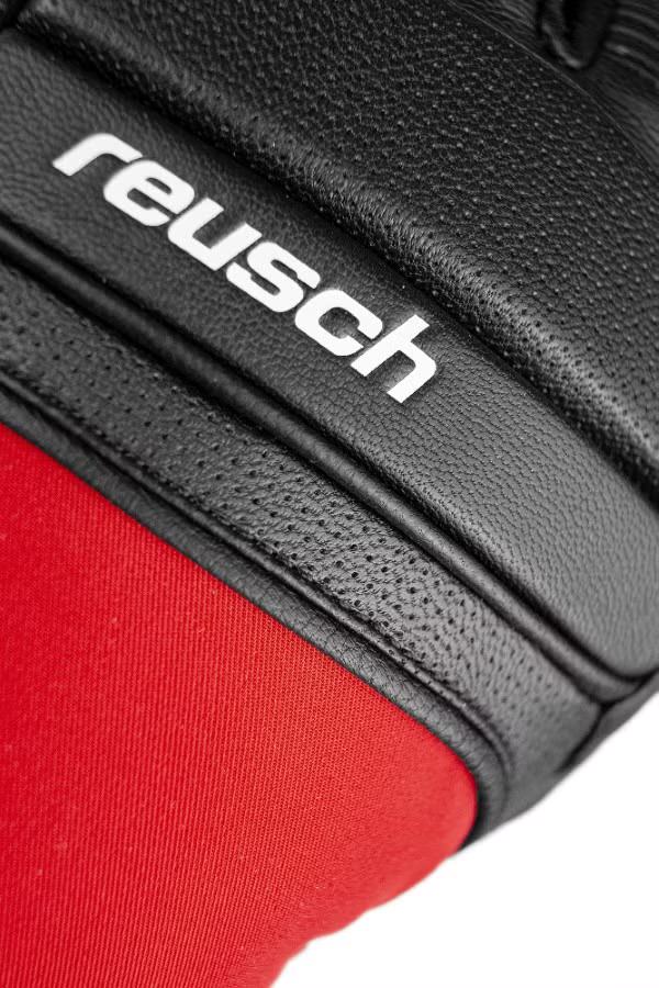 Reusch Marco Odermatt Handschuh Detailaufnahme des schwarzen Reusch Marco Odermatt Handschuhs mit rotem Stoff und dem weißen Reusch-Logo.