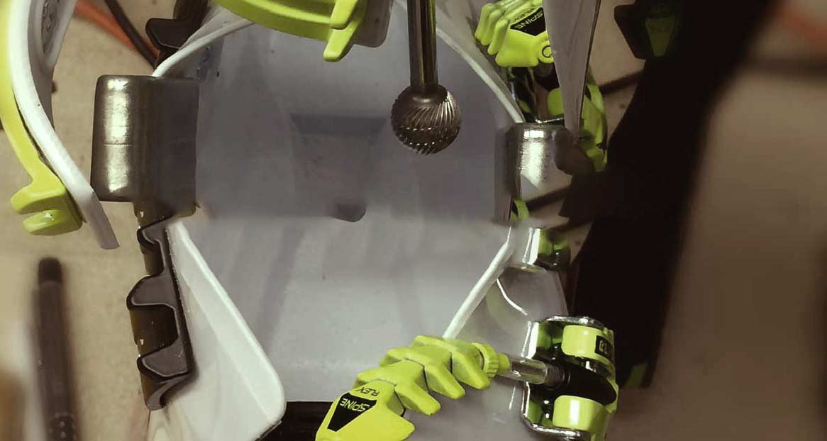 Innenansicht eines Skischuhs mit Anpassungswerkzeug und gelben Spine Flex Elementen. Metallteile und Kunststoffelemente sind sichtbar.