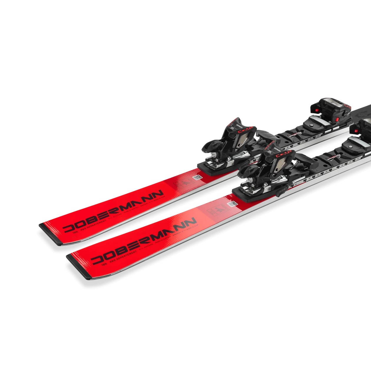 Deux skis Dobermann rouges, blancs et noirs avec fixations sont posés parallèlement sur un fond blanc.