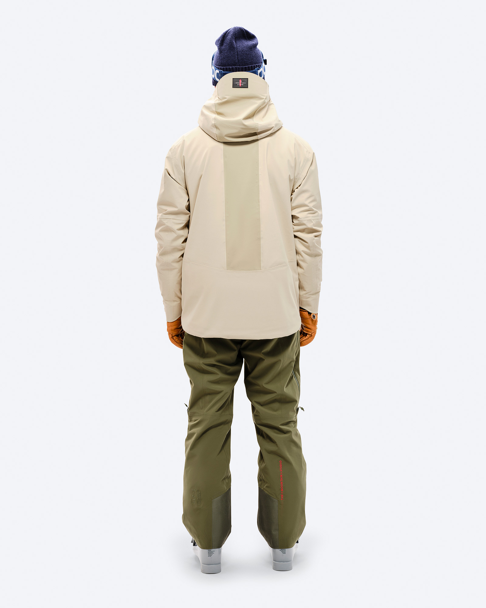 Z-5 Hybrid Jacket Rückansicht Rückansicht einer Person mit der Z-5 3L Hybrid Shell Jacket in Beige, kombiniert mit grüner Hose und braunen Handschuhen.