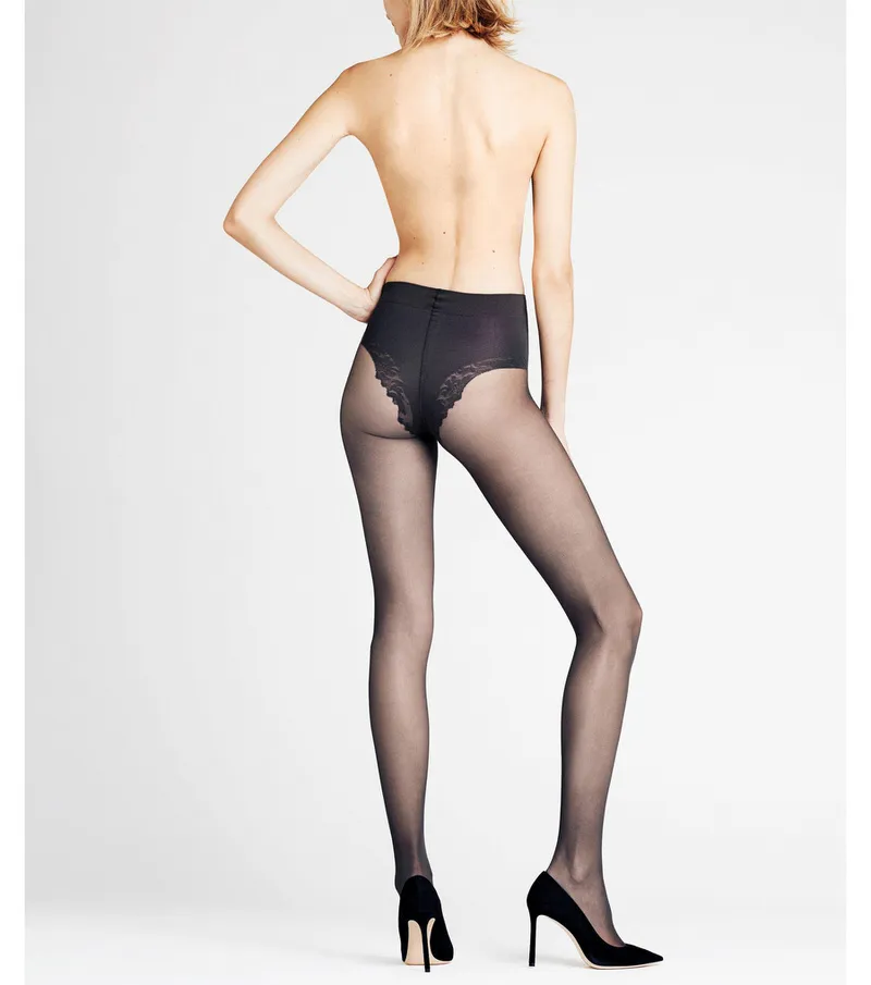 Rear view of a woman wearing black, transparent 20 DEN shaping top tights and black shoes.