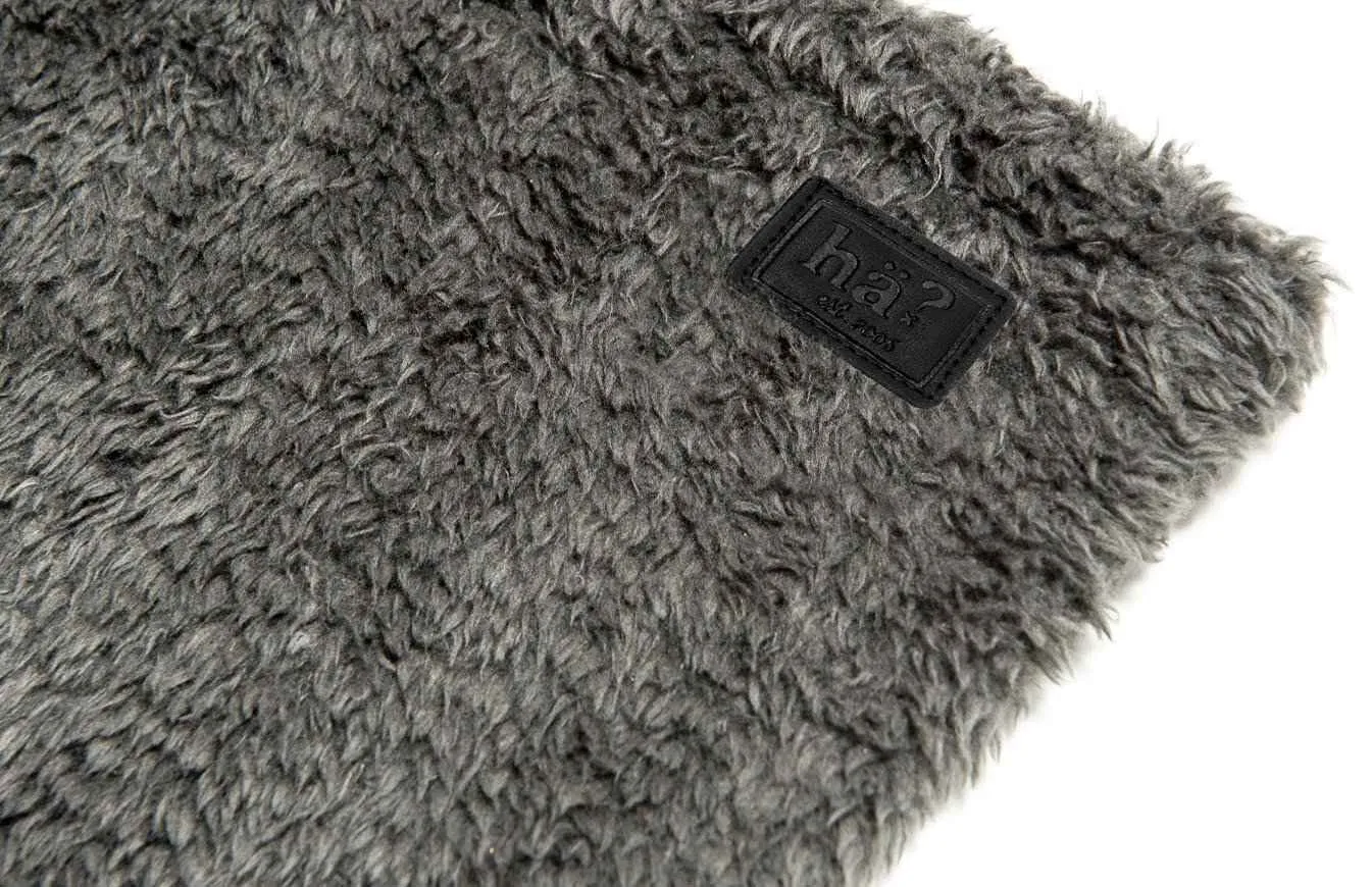Primo piano di uno scaldacollo wellness grigio con soffice pile polare e patch in pelle con logo.