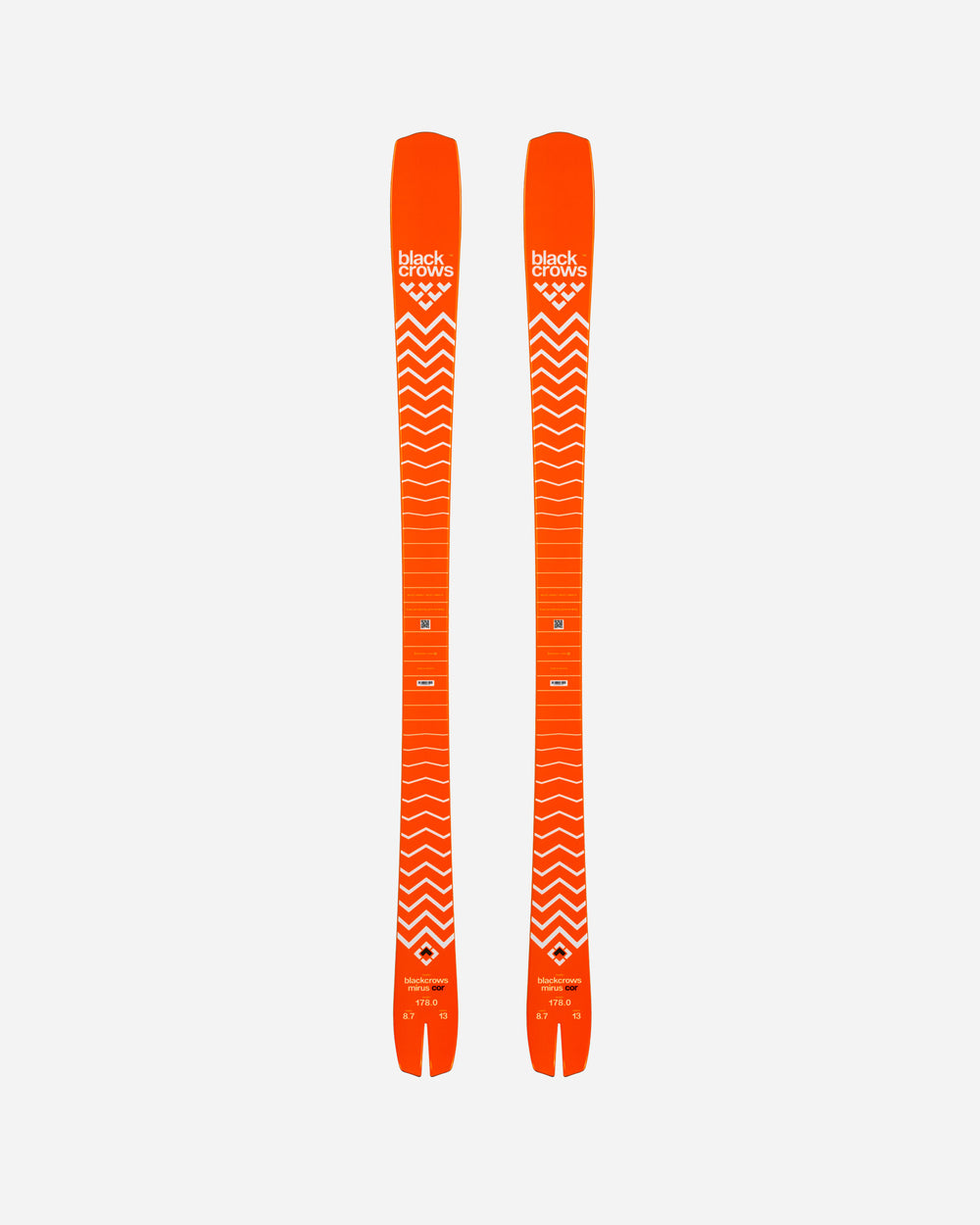 Deux skis orange avec un motif en zigzag blanc sur fond blanc, vus de dessus. Sur le ski se trouve l'inscription "black Crows".