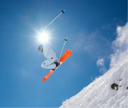 Sciatore con gli sci Black Crows Draco Freebird che salta davanti al cielo blu e alla neve.