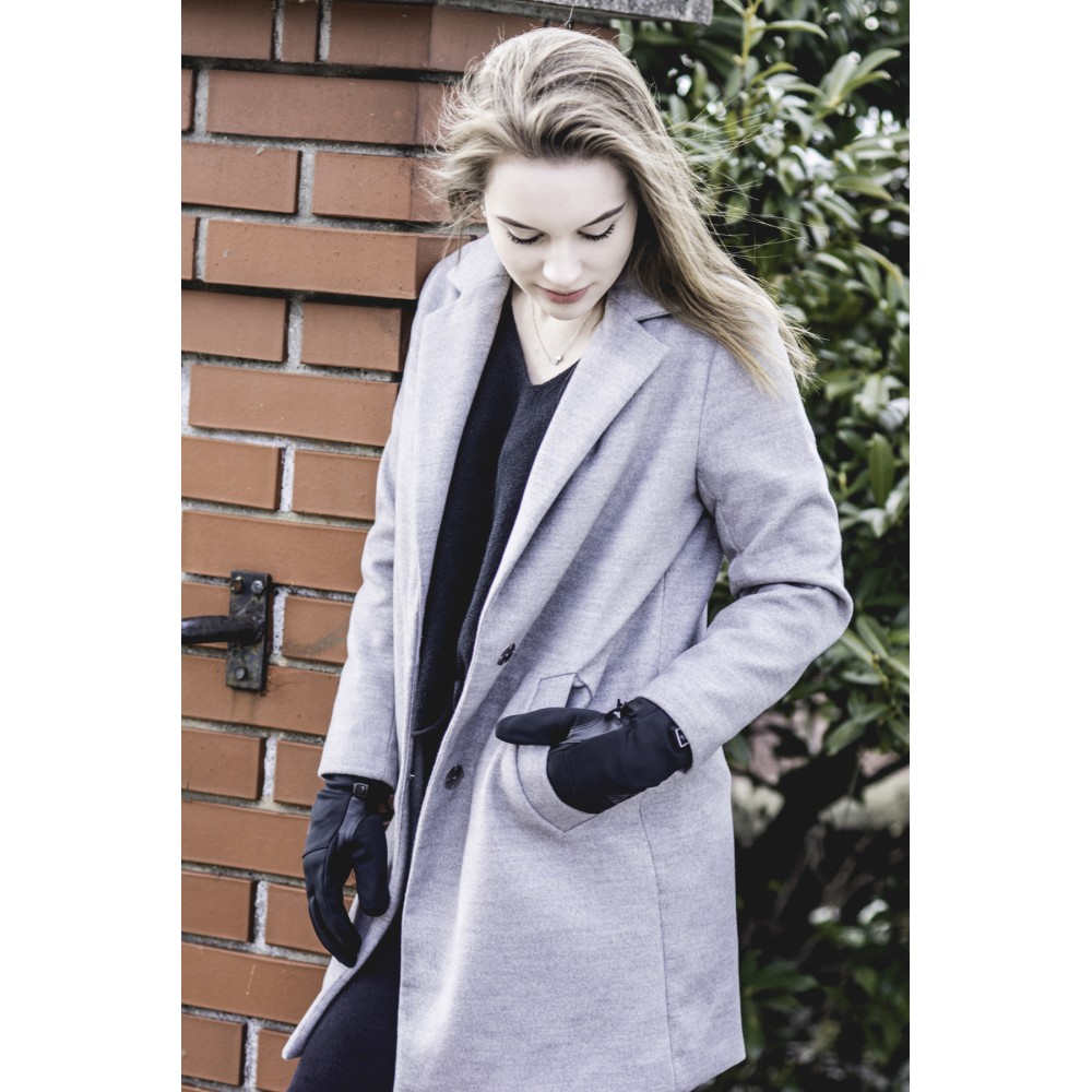 Junge Frau mit langem blonden Haar, trägt grauen Mantel und Fire Glove Everyday Handschuhe.