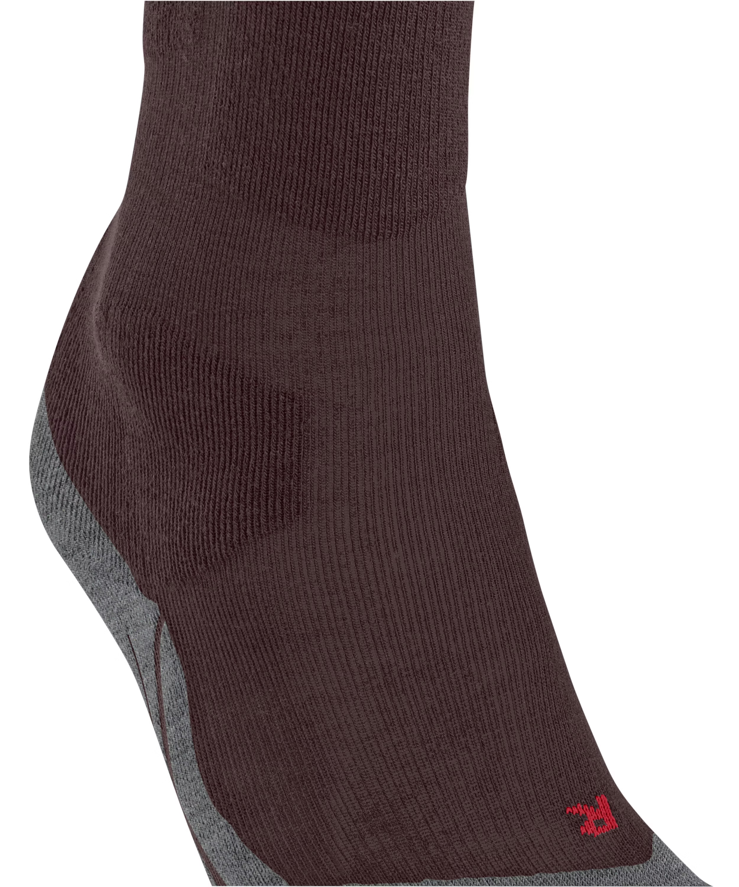 Nahaufnahme eines dunkelbraunen Sockens, der den Knöchel, die Ferse und einen Teil des Fußrückens bedeckt. Geripptes Strickmuster, Ferse mit grauem Stoff verstärkt. Seitlich kleines gesticktes rotes Logo.