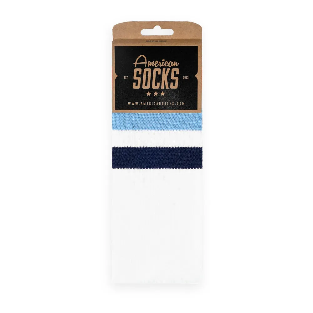 Packaged, white mid high socks with light blue and dark blue stripes.