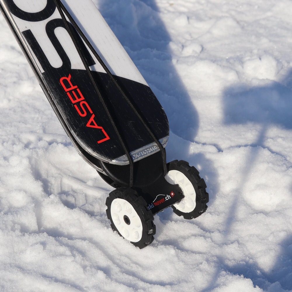 Skis with mounted Skimover Easy wheels in the snow, close-up.
