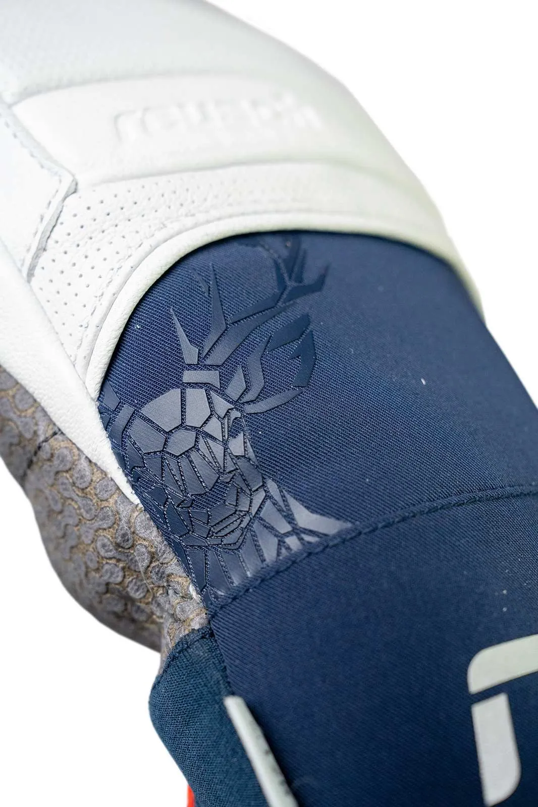 Close-up of a white and blue glove with a stylized stag's head emblem.