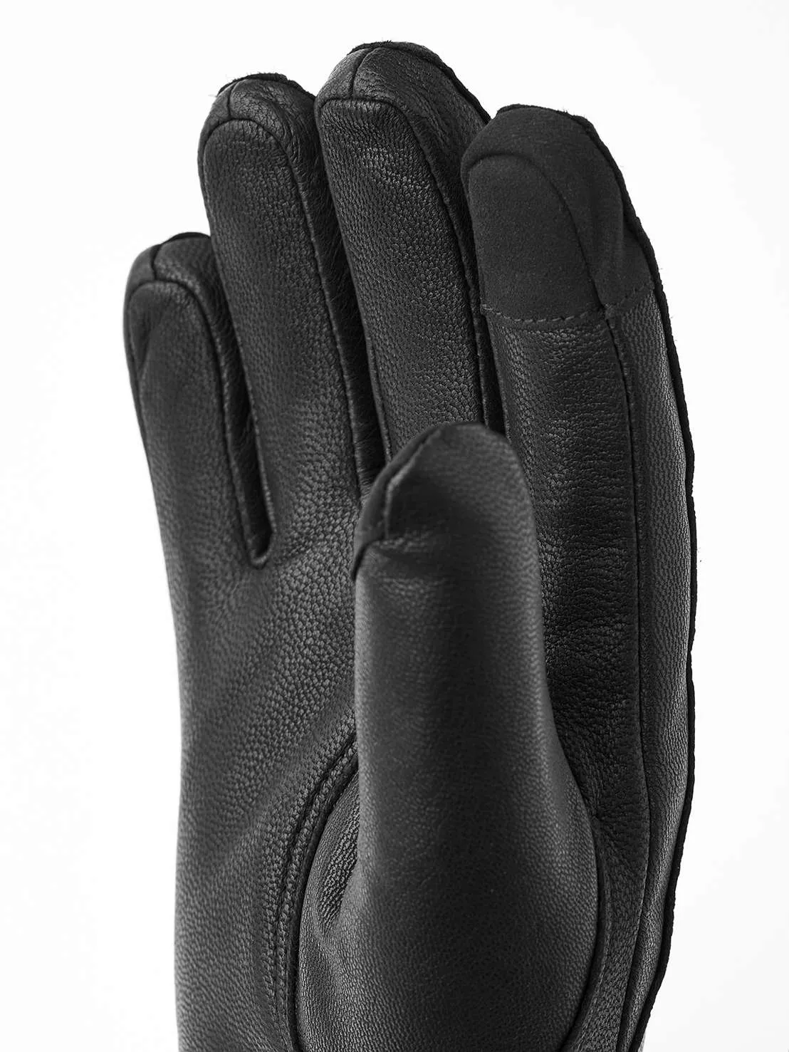 Détail d'un gant en cuir noir formant un poing, avec la texture du cuir visible.