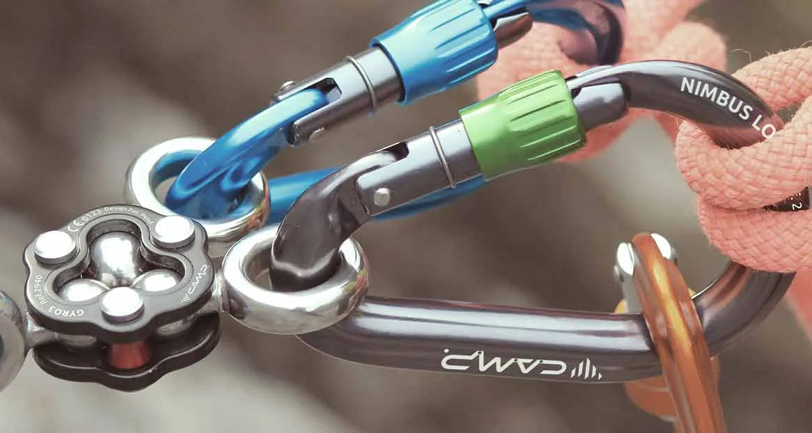 Close-up of climbing equipment with snap hooks, rope, pulley and other metal elements in different colors.