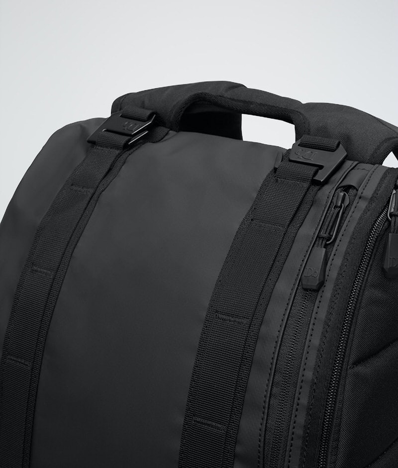 Detailansicht des Douchebags The Base 15L Rucksacks in Schwarz, mit Fokus auf Tragegriff, Gurte und Reißverschlüsse.