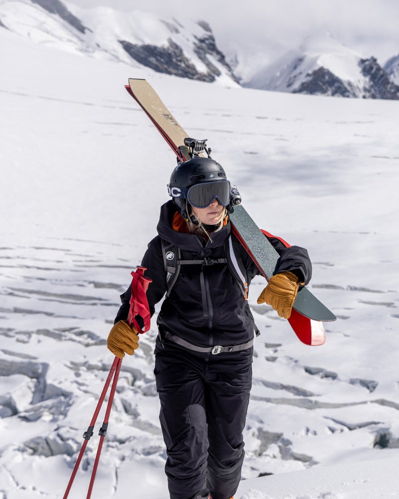 Skieur dans un paysage de montagne Personne portant une veste Gore-Tex noire et un pantalon de ski avec des skis et des bâtons dans un paysage de montagne enneigé.