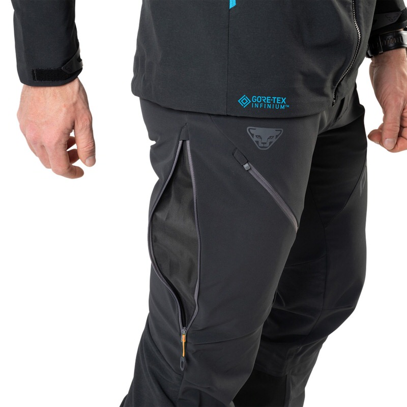 Primo piano dei pantaloni ibridi Dynafit Radical Infinium neri da uomo, con cerniere e logo Gore-Tex Infinium.