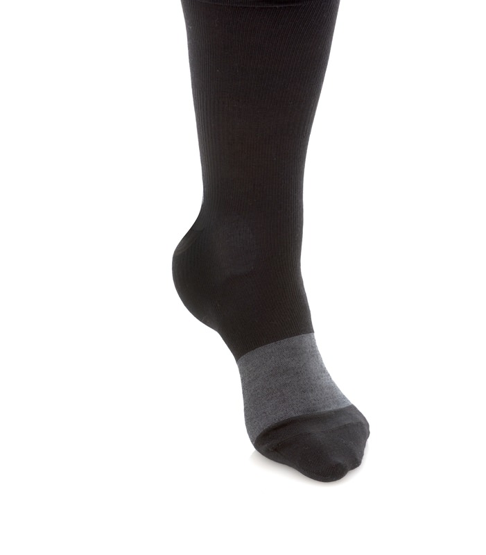 Chaussette noire avec pied gris Pied avec chaussette noire, zone de la cheville en gris, isolée sur fond blanc.
