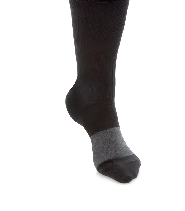 Pied avec chaussette noire, zone de la cheville en gris, isolée sur fond blanc.