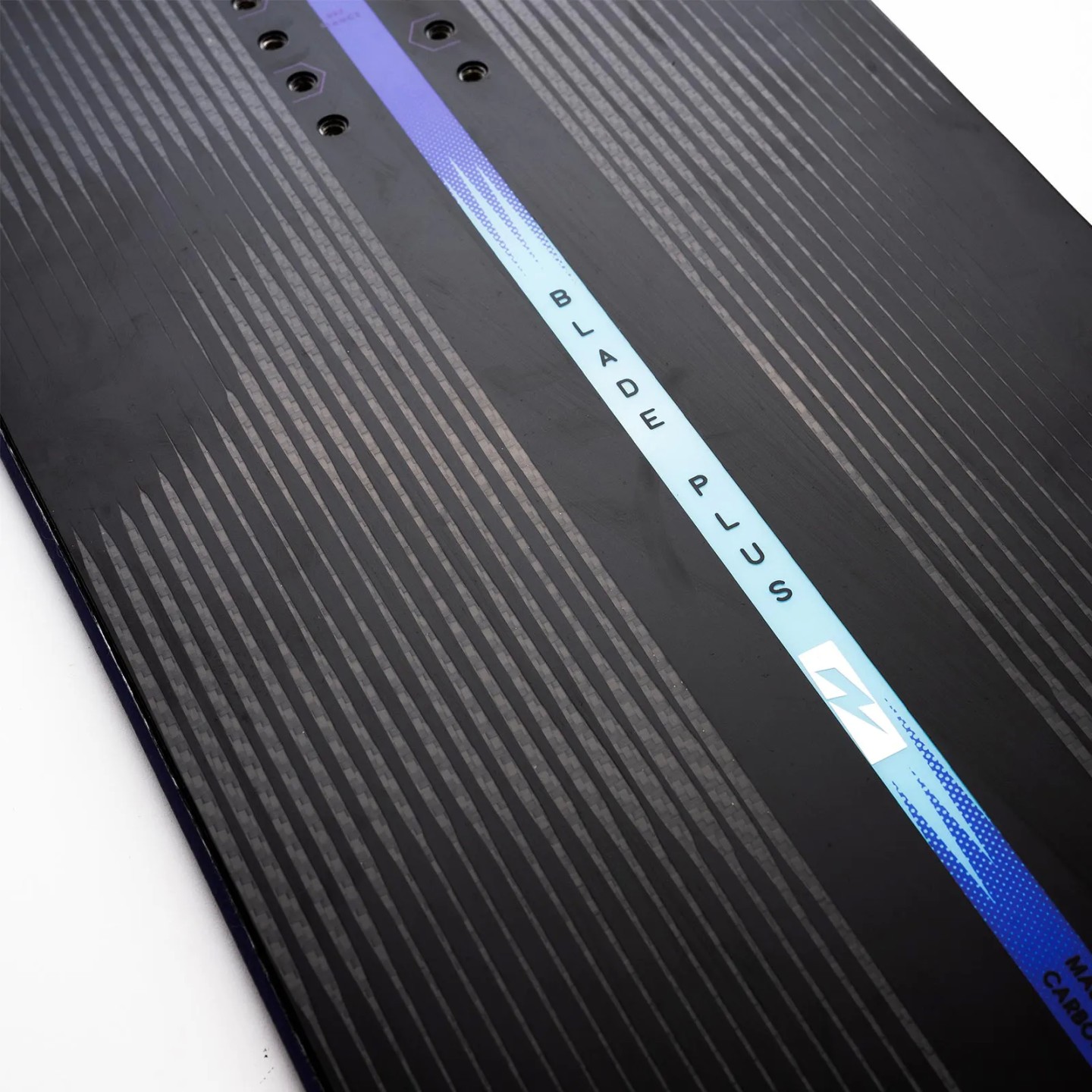 Nidecker Blade Plus Snowboard Detailansicht des Nidecker Blade Plus Snowboards mit dunkelgrauem Muster und blauem Streifen mit dem Schriftzug "Blade Plus".