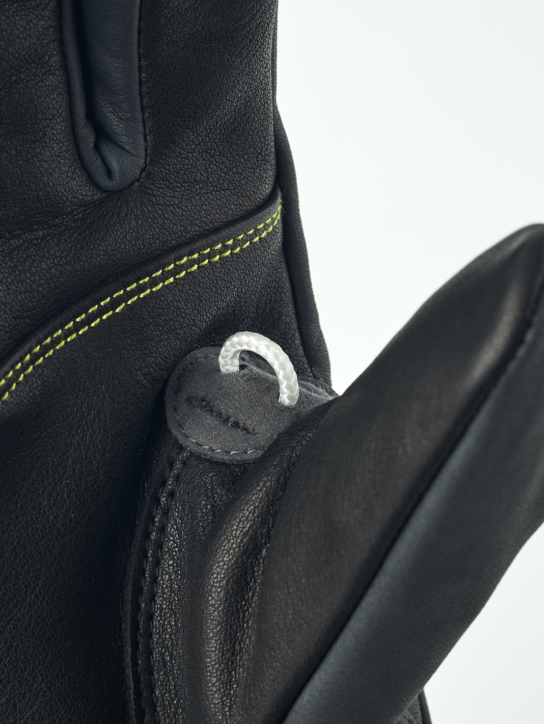 Detailaufnahme eines schwarzen Lederhandschuhs mit gelben Nähten und einer kleinen weißen Schlaufe.