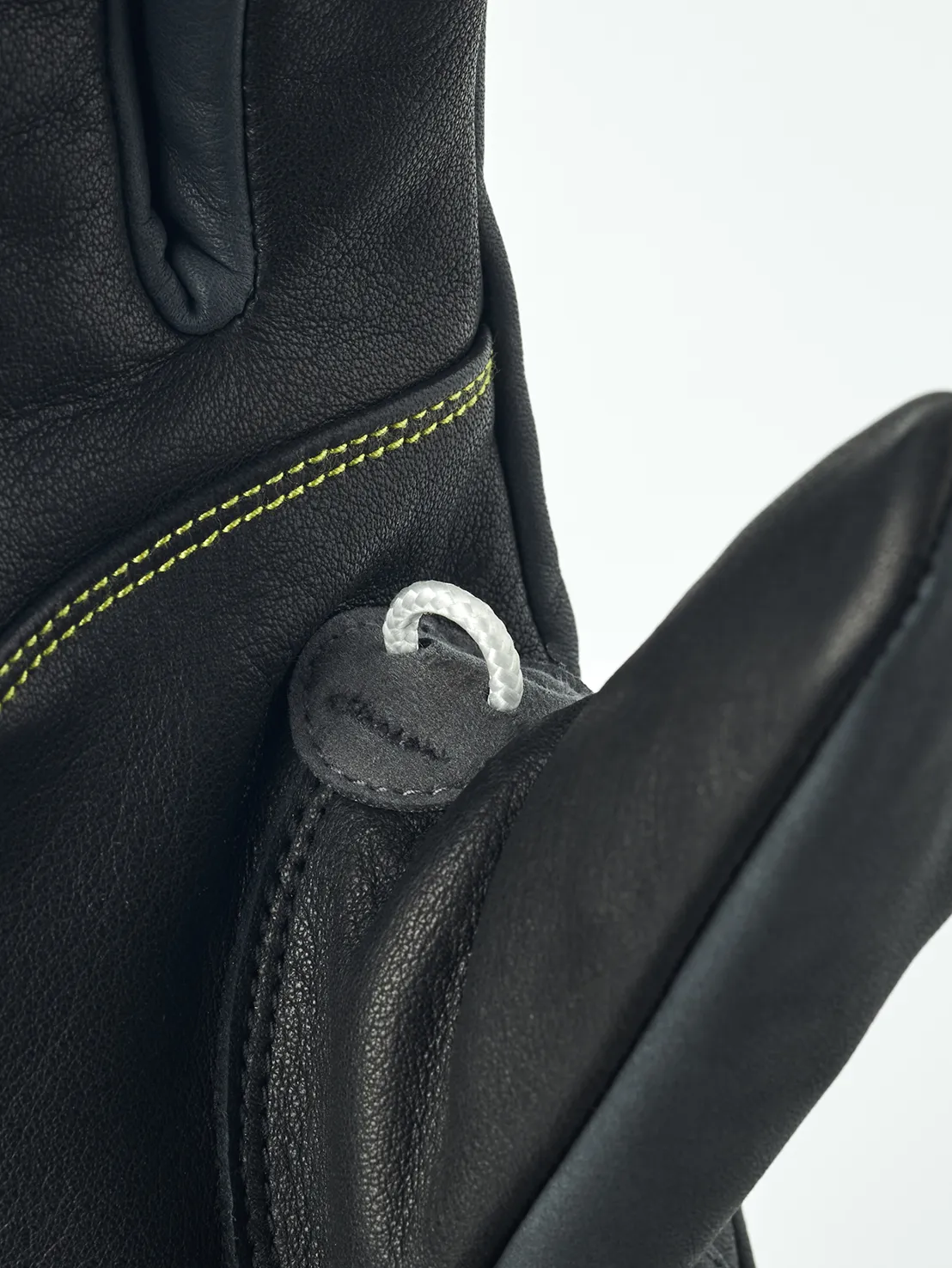 Detailaufnahme eines schwarzen Lederhandschuhs mit gelben Nähten und einer kleinen weißen Schlaufe.