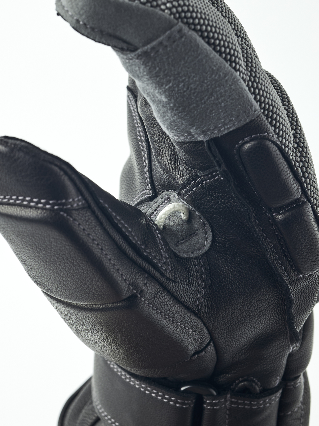 Nahaufnahme eines schwarzen Lederhandschuhs, der eine Hand darstellt. Details wie Nähte und Texturen sind sichtbar.