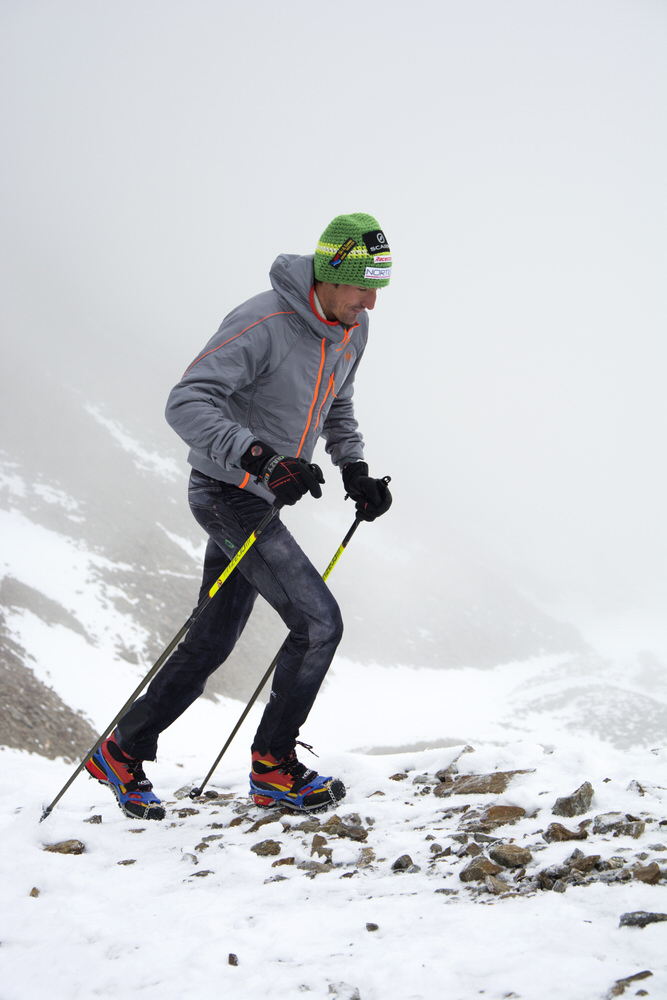 Bergsteiger im Schnee Mann mit Trekking Steigeisen und Stöcken im Schnee, Aufstieg in bergiger Landschaft.
