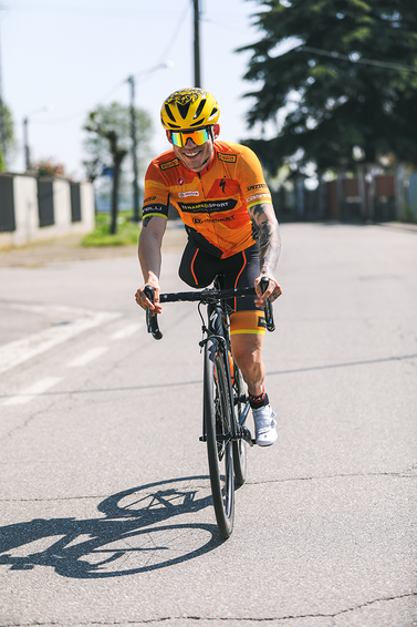 Radfahrer auf Asphalt Radfahrer mit gelbem Helm und polarisierter Brille auf einer asphaltierten Straße.