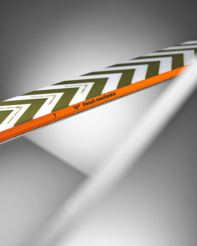 Detailansicht eines Skis mit Zickzackmuster in Grün und Weiß sowie einem orangen Streifen. "French mechanics" ist aufgedruckt.