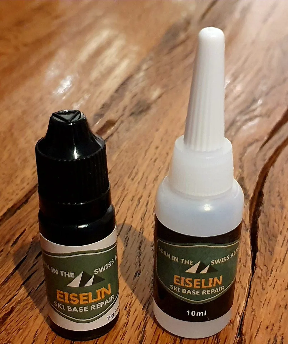 Zwei Flaschen: Schwarze Flasche Pulver, weiße Flasche Kleber für die Ski Belag Reparatur.