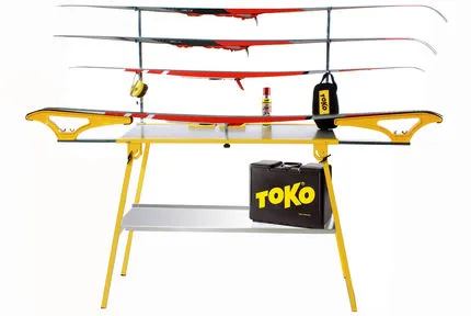Gelber Servicetisch mit Ski, Ablageblech, Wachs, Werkzeug und Toko Tasche.