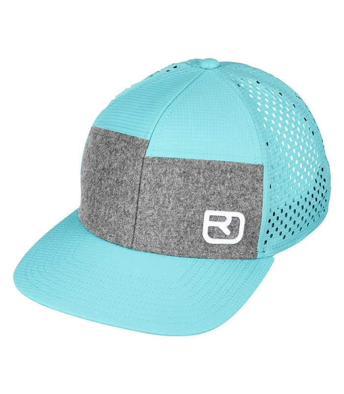 Casquette Trucker bleu glacier avec bande de tissu grise et logo blanc Ortovox, structure en filet à l'arrière de la tête.
