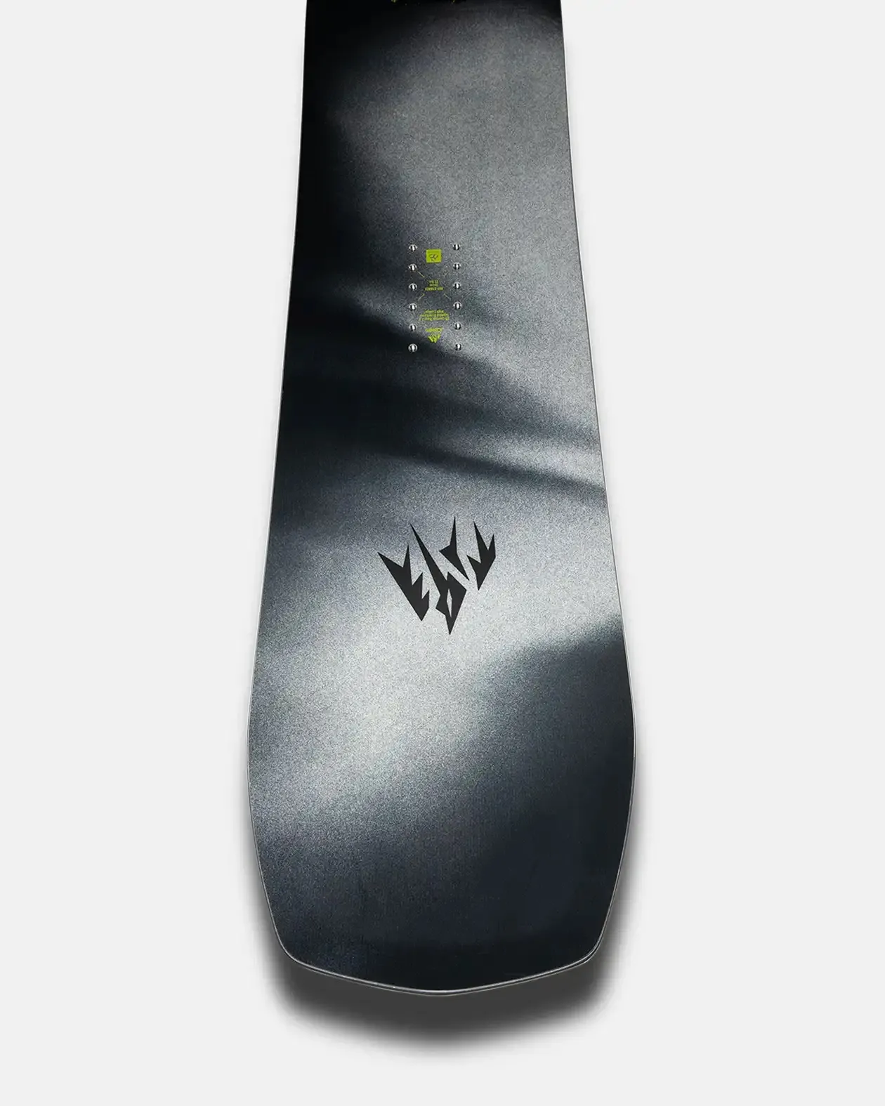 Una tavola da snowboard con design e logo in nero. La tavola presenta punti di fissaggio al centro e una sfumatura di colore dal grigio chiaro al nero.