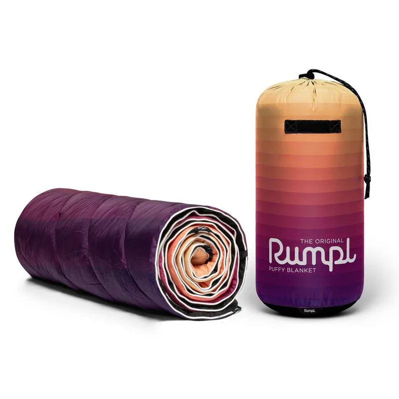 Rumpl Original Puffy Blanket Dawn Pixel: Gerollte Decke und Packsack mit Farbverlauf.