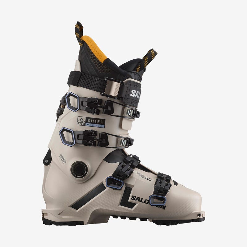 Chaussure de ski beige Salomon Shift Pro 130 AT vue de côté, avec des boucles noires et un chausson jaune.