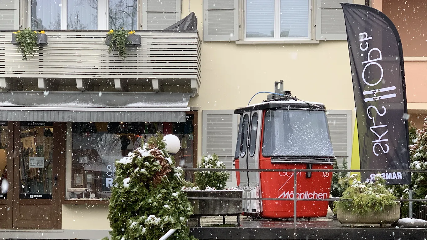 Ein rotes Gondel-Modell vor einem Laden mit einem "Ski-Ob" Banner im Schneefall.
