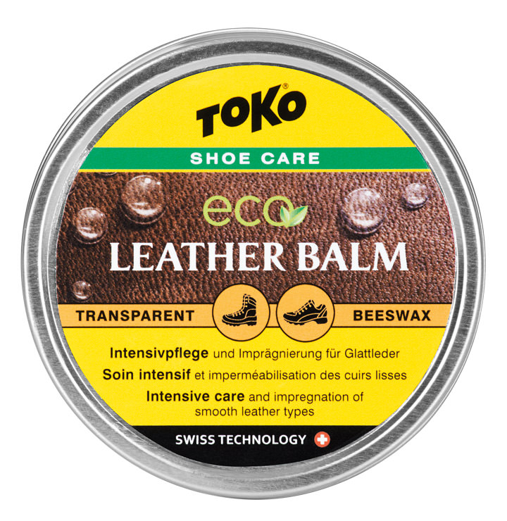 Toko Eco Lederbalsam Dose Toko Eco Leather Balm mit gelbem Etikett und Lederhintergrund. Enthält Text und Piktogramme für Schuhpflege.