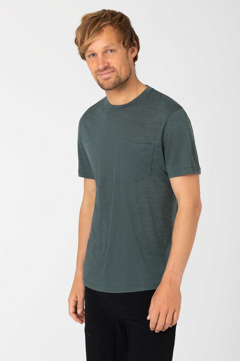 T-shirt décontracté couleur pétrole L'homme porte un T-shirt pétrole chiné avec une poche poitrine et un pantalon noir. Décontracté, regard sur le côté.