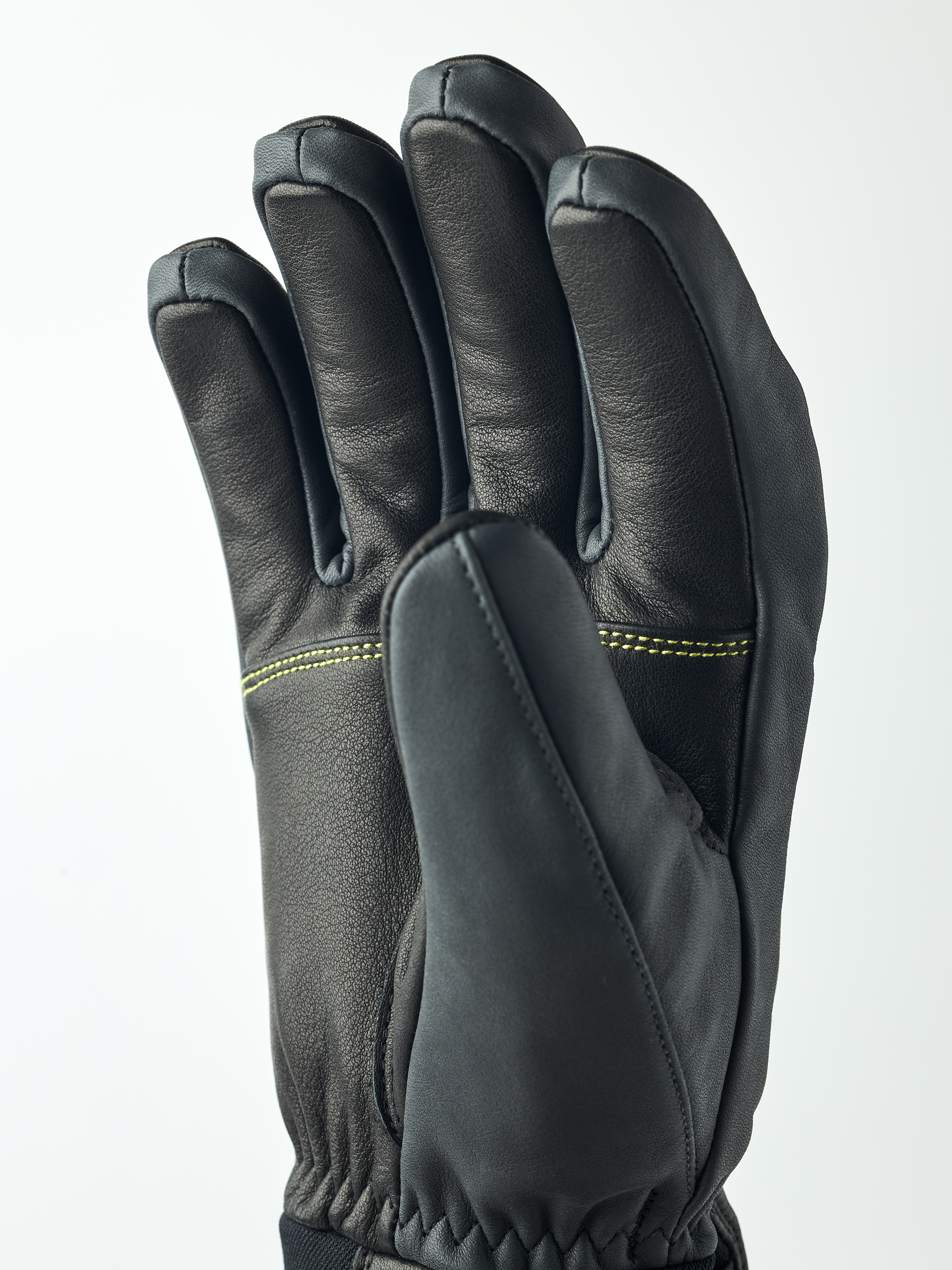 Hestra Omni Trigger Handschuh Schwarzer Hestra Omni Trigger Handschuh von Nahem, die Hand ist leicht geöffnet und zeigt die Finger. Gelbe Nähte sind sichtbar.