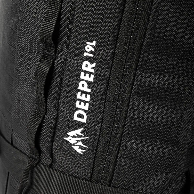 Detailaufnahme: Schwarzer Jones Deeper 19L Rucksack, Logo mit stilisiertem Berg und Reißverschluss.