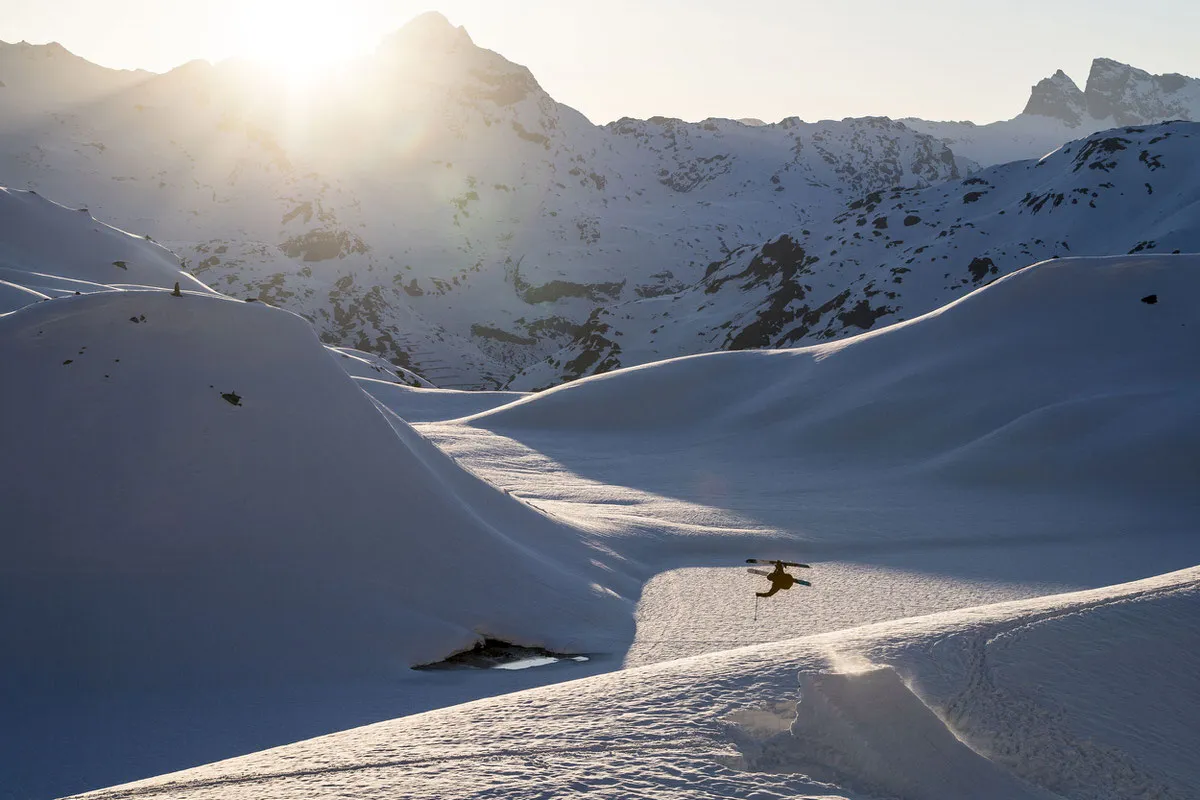 Snowy mountain landscape with skier making a jump. Griffon 13 ID binding suitable for freestyle moves.